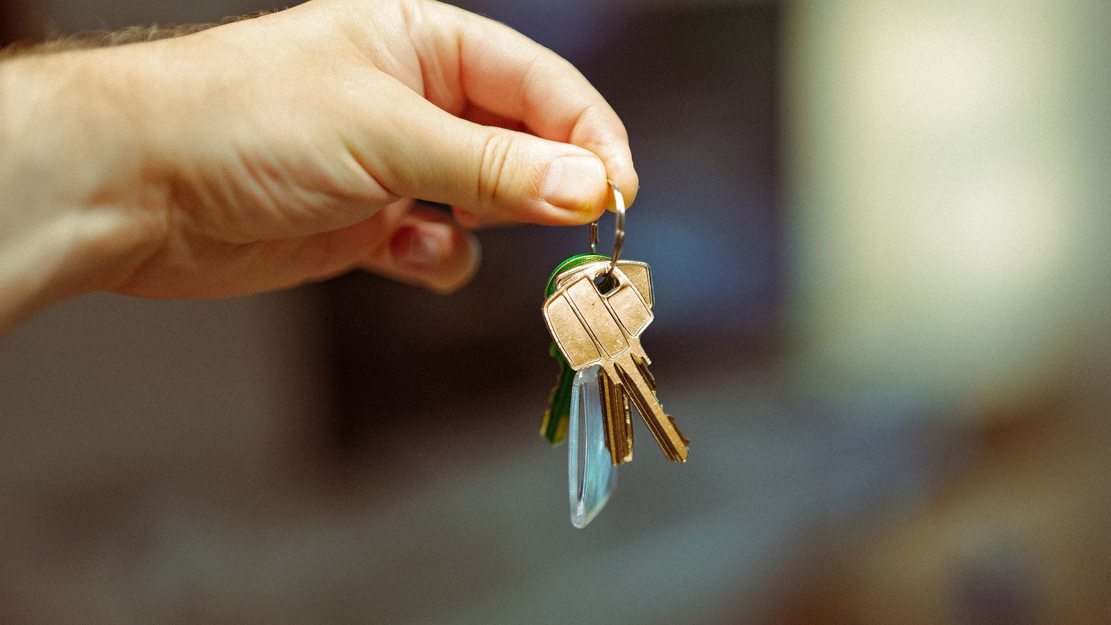 Hand holding a set of house keys against a soft background