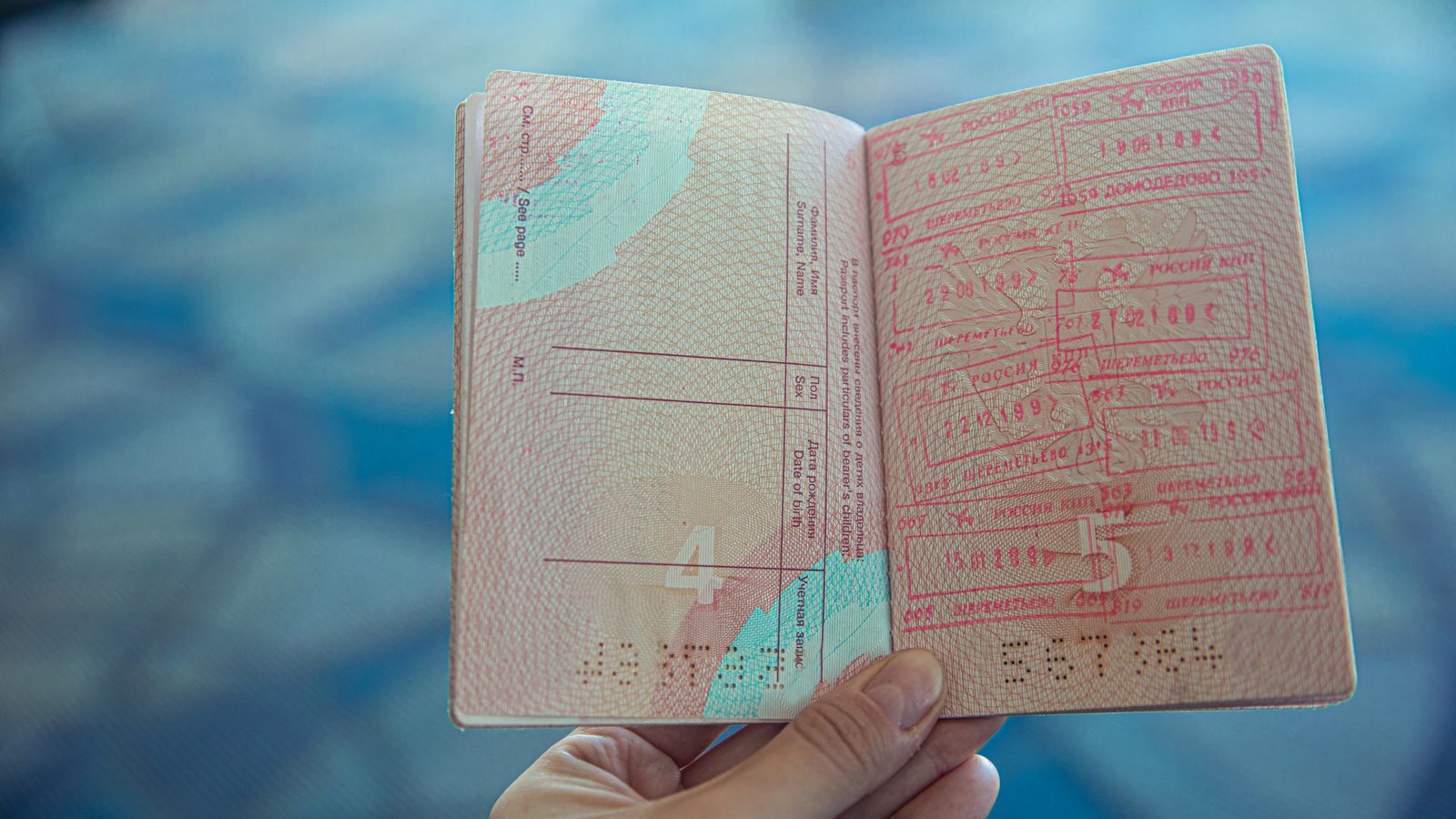Hand holding an open passport full of entry stamps