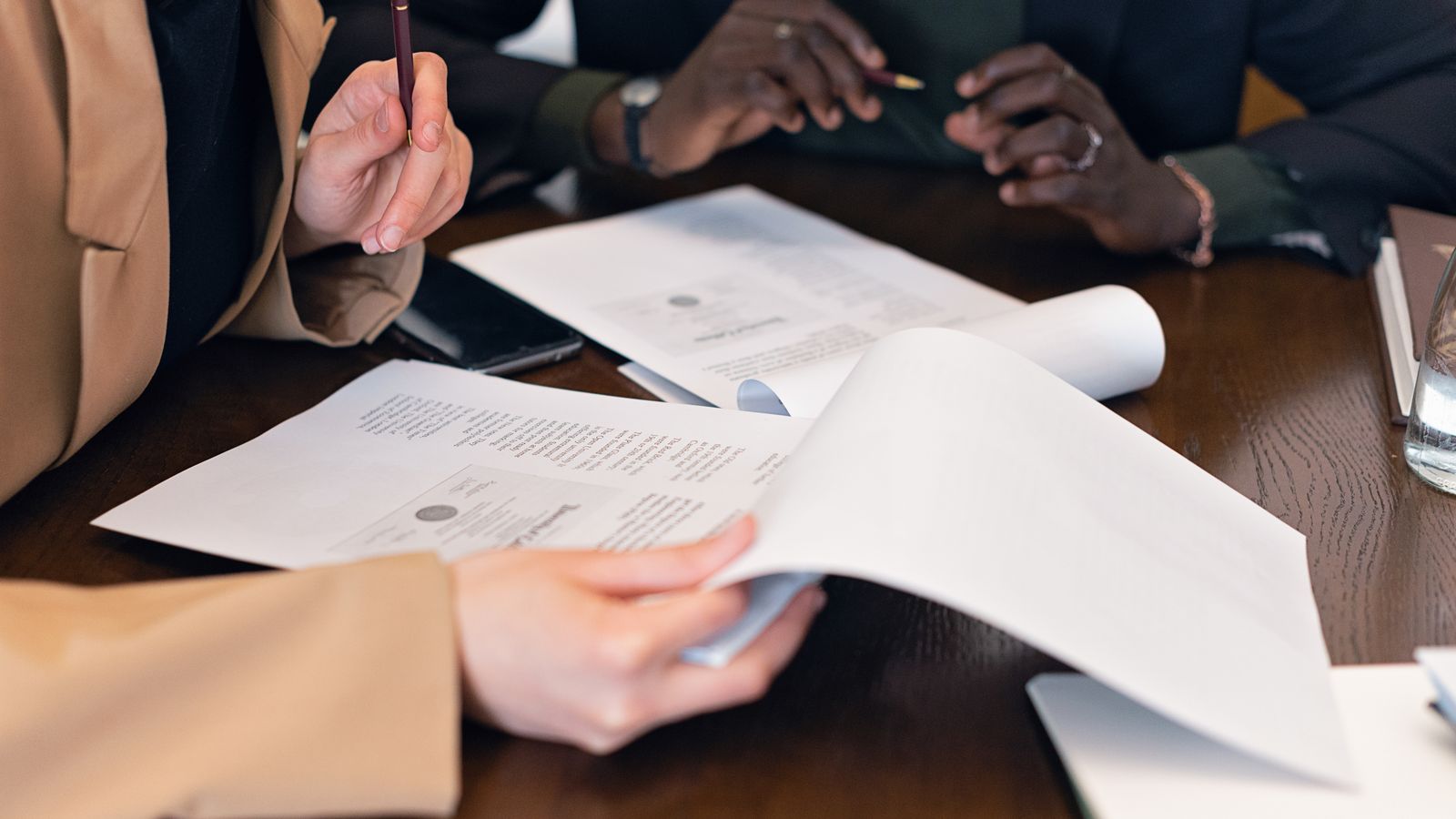 Two people comparing paper documents across a table