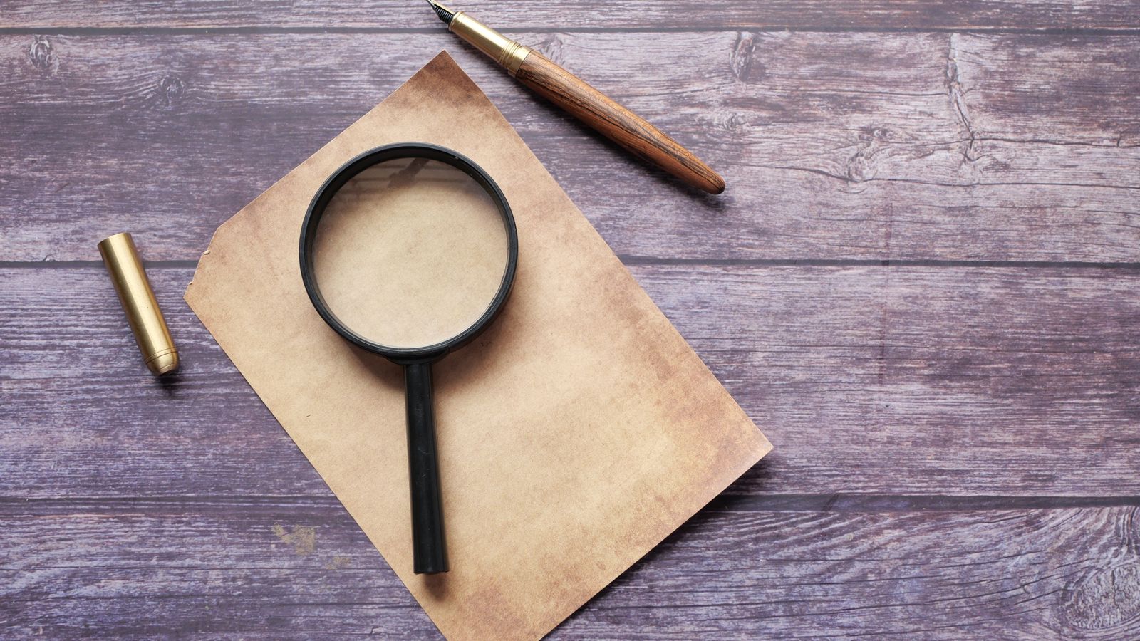 Magnifying glass lying on a sheet of paper beside a pen